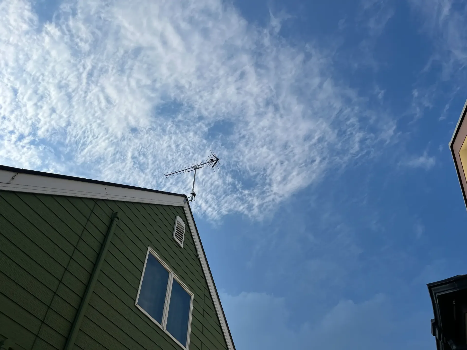 青空の下で屋根上のアンテナを調整する施工写真